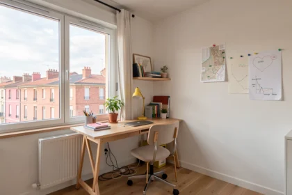 Studio étudiant lumineux avec bureau face aux toits de briques roses de Toulouse
